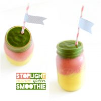 Two jars filled with our Stoplight Mango Green Smoothie recipe with flag straws in them