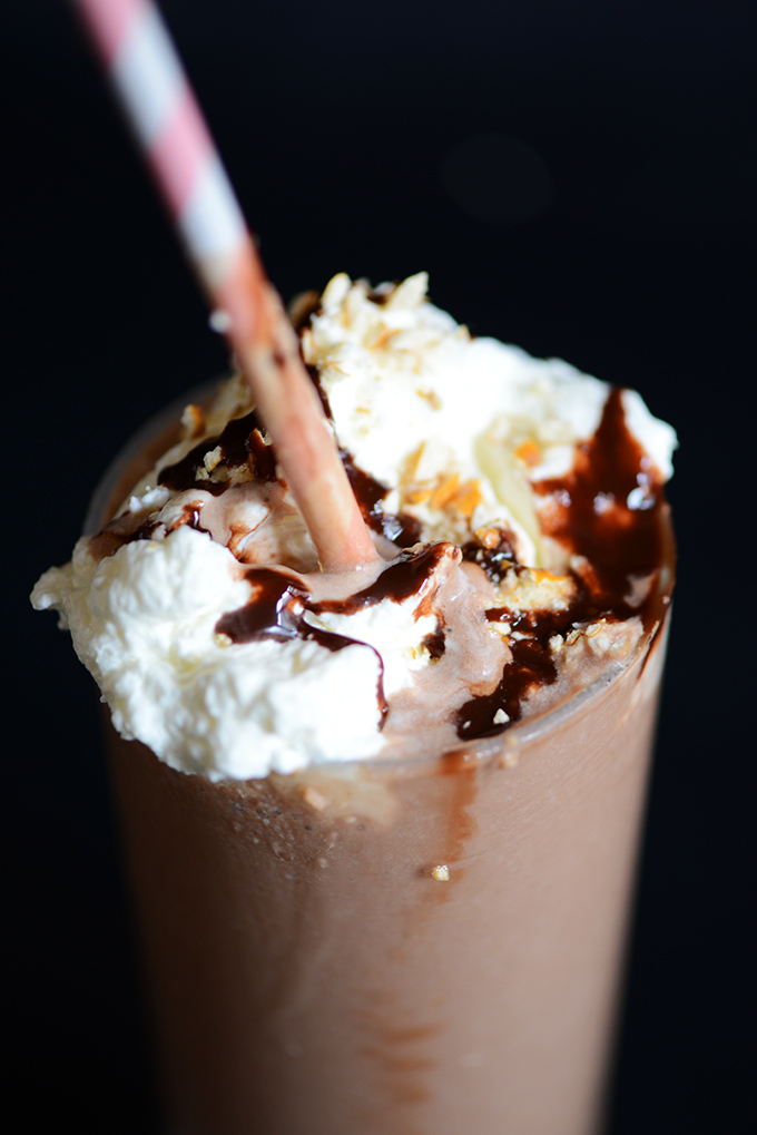 Tall glass of Pretzel Frozen Hot Chocolate topped with coconut whip and chocolate sauce