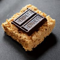 Homemade S'mores Rice Krispie Treat topped with two pieces of Hershey's chocolate