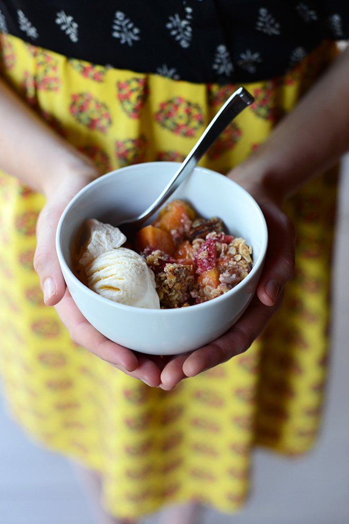 Holding a bowl of our delicious Gluten-Free Summer Fruit Crisp recipe