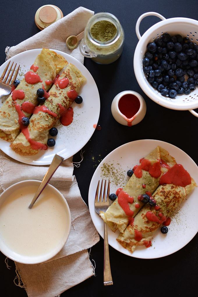 Plates of Gluten-Free Green Tea Crepes surrounded by ingredients used in the filling and topping