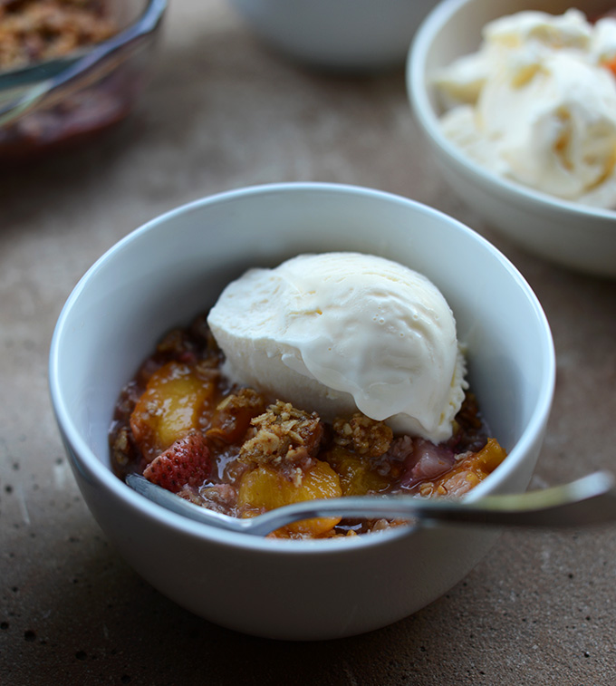Close up shot of a bowl of Gluten-Free Summer Fruit Crisp with ice cream