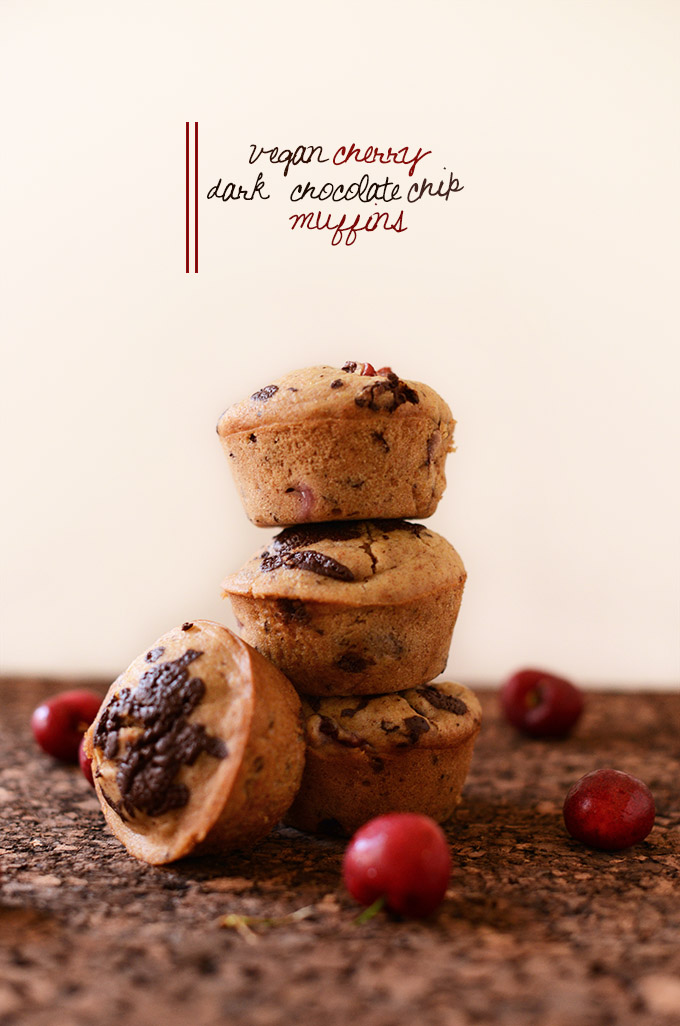 Stack of Vegan Cherry Dark Chocolate Chip Muffins with fresh cherries scattered around
