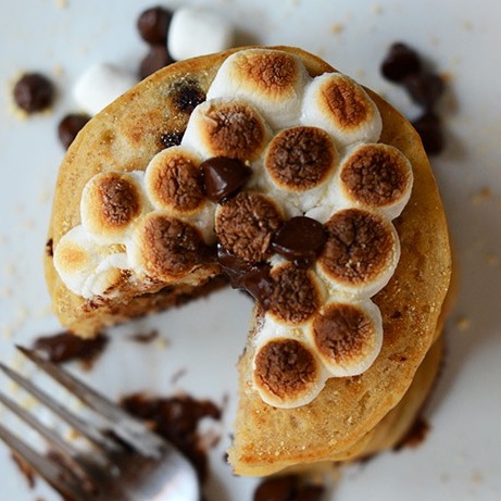Top down shot of a stack of Vegan Smores Pancakes topped with toasted marshmallows and chocolate chips