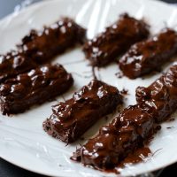 Plate of homemade Vegan Snickers Bars on plastic wrap