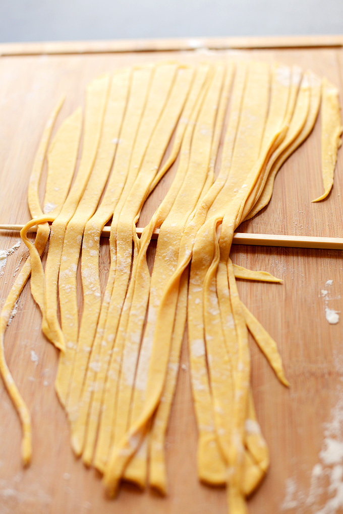 Strips of homemade pumpkin pasta with a skewer under them