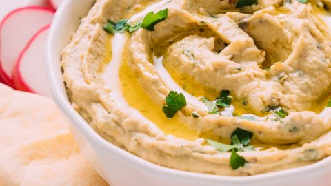 Large bowl of homemade Baba Ganoush beside pita bread and vegetables for a delicious and simple appetizer