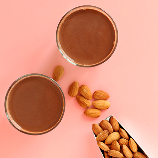 Scoop of almonds and two glasses of our DIY Chocolate Almond Milk recipe