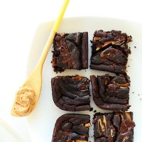 Spoonful of peanut butter and plate with slices of our Peanut Butter Swirl Black Bean Brownies
