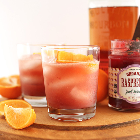 Glasses of our winter bourbon smash recipe on a wood cutting board