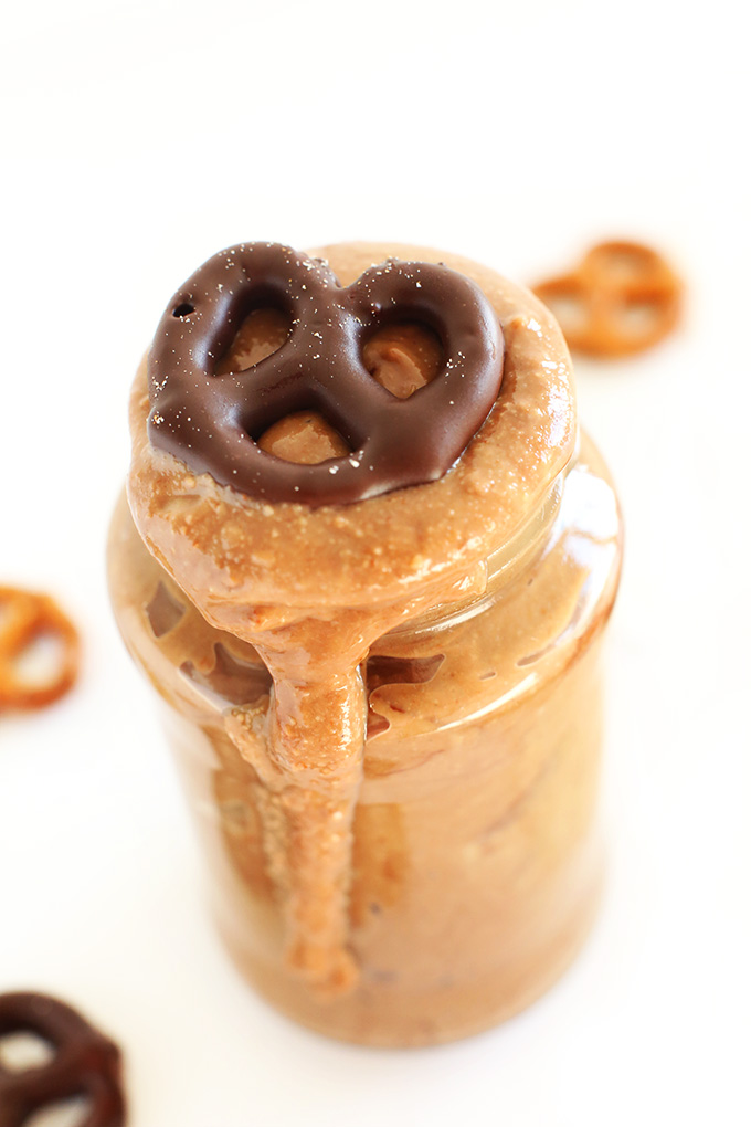 Overflowing jar of homemade peanut butter with a chocolate pretzel on top