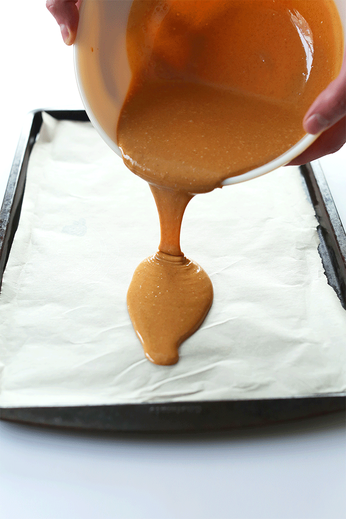 Pouring a batch of DIY Peanut Butter Chip batter onto a parchment-lined baking sheet