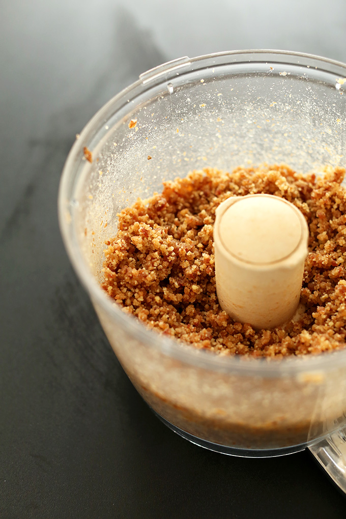 Food processor filled with freshly pulsed raw vegan pie crust dough
