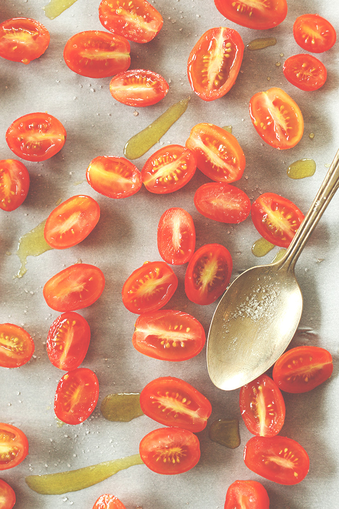 Baking sheet with halved cherry tomatoes drizzled with olive oil for roasting