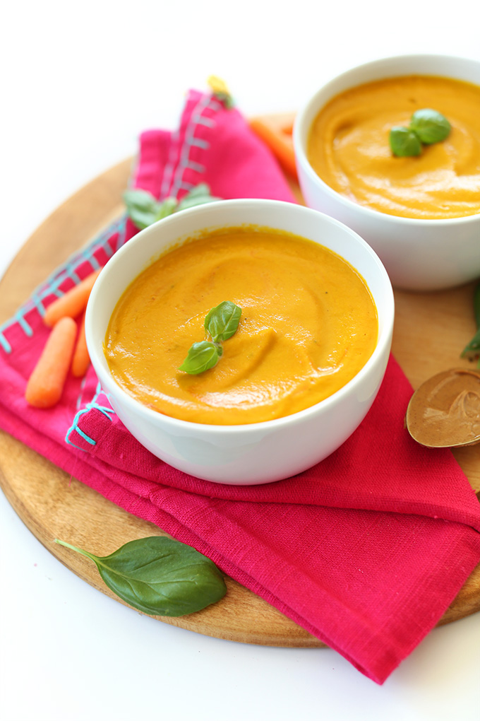 Bowls of Creamy Carrot Soup topped with fresh basil leaves