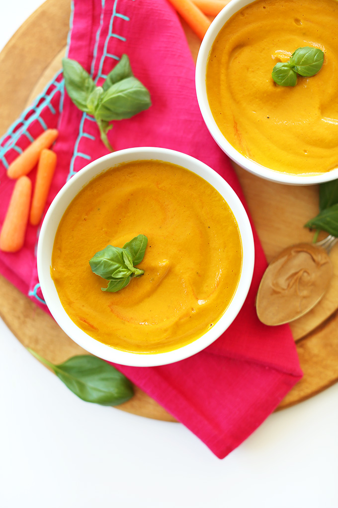 Bowls of Creamy Vegan Carrot Soup made with peanut butter and topped with fresh basil