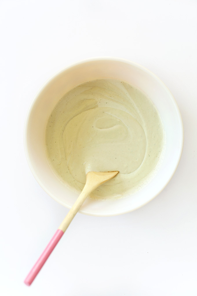 Using a wooden spoon to stir together ingredients for Creamy Vegan Mint Ice Cream