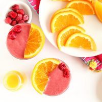 Top down shot of two glasses of Summer in a Cup Smoothie with fresh raspberries and orange slices