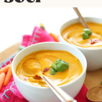 Two bowls of our creamy 30-minute Thai-inspired carrot soup topped with sriracha and fresh basil