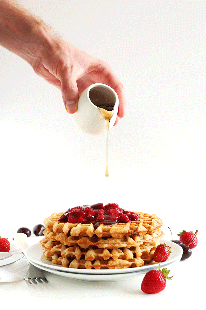 Pouring maple syrup over a stack of our vegan gluten-free waffles recipe