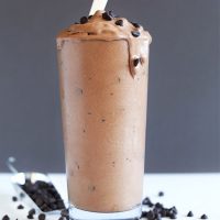 Side view of a glass of our Vegan Chocolate Chocolate Chip Blizzard recipe topped with more chocolate chips
