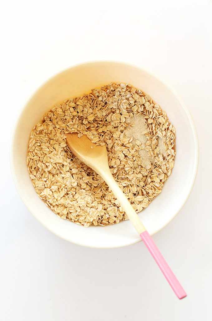 Wooden spoon in a bowl of dry ingredients for Peanut Butter Chocolate Chip Granola