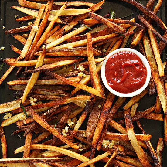Crispy Baked Garlic Fries on a baking sheet with a bowl of ketchup