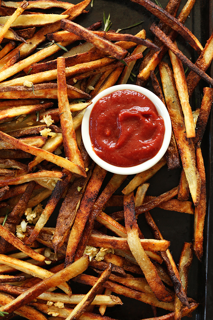 Baking sheet filled with homemade baked french fries and ketchup