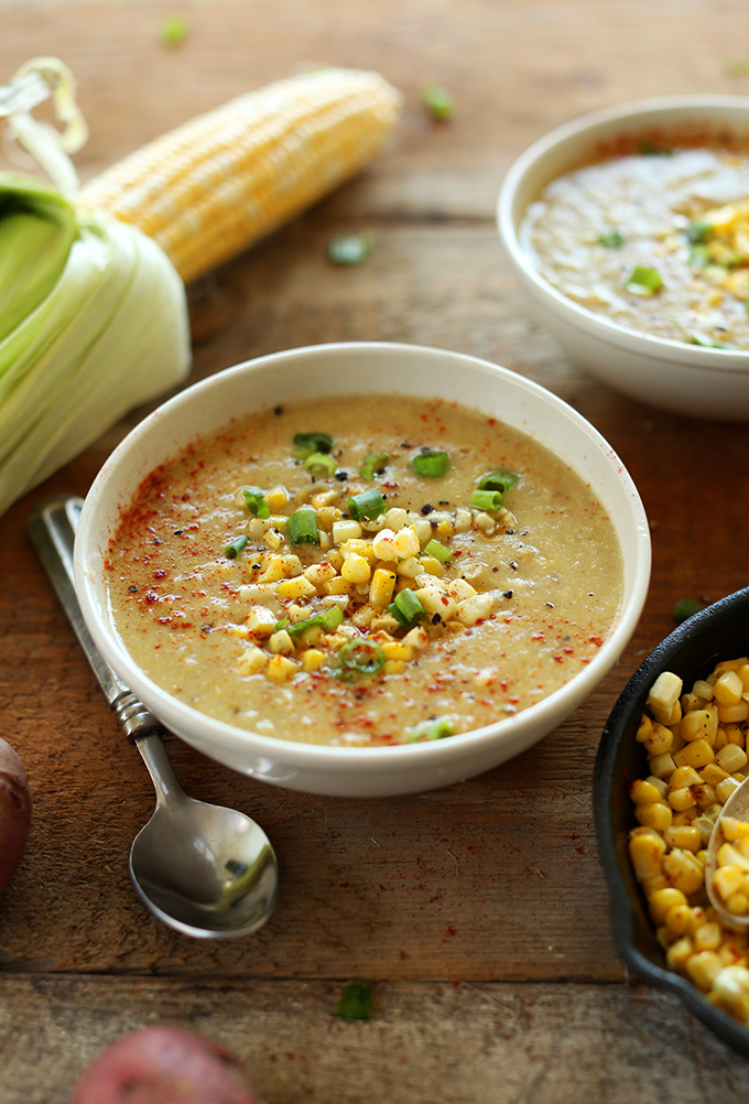 Close up shot of a bowl of Vegan Corn Chowder topped with green onion and corn