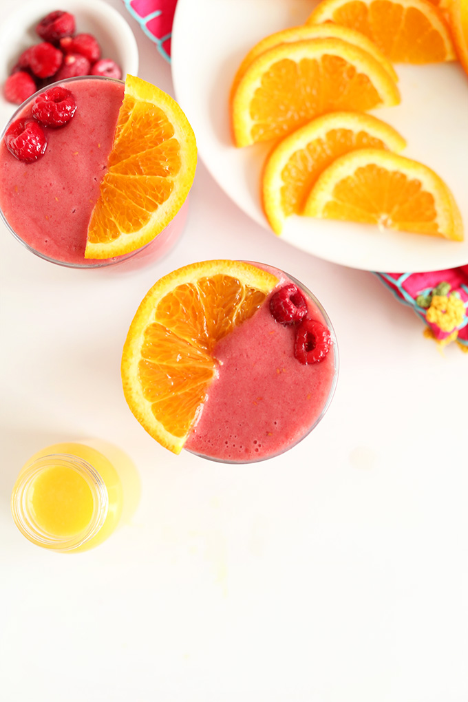 Orange slices, fresh raspberries, and two glasses of our Summer in a Cup smoothie