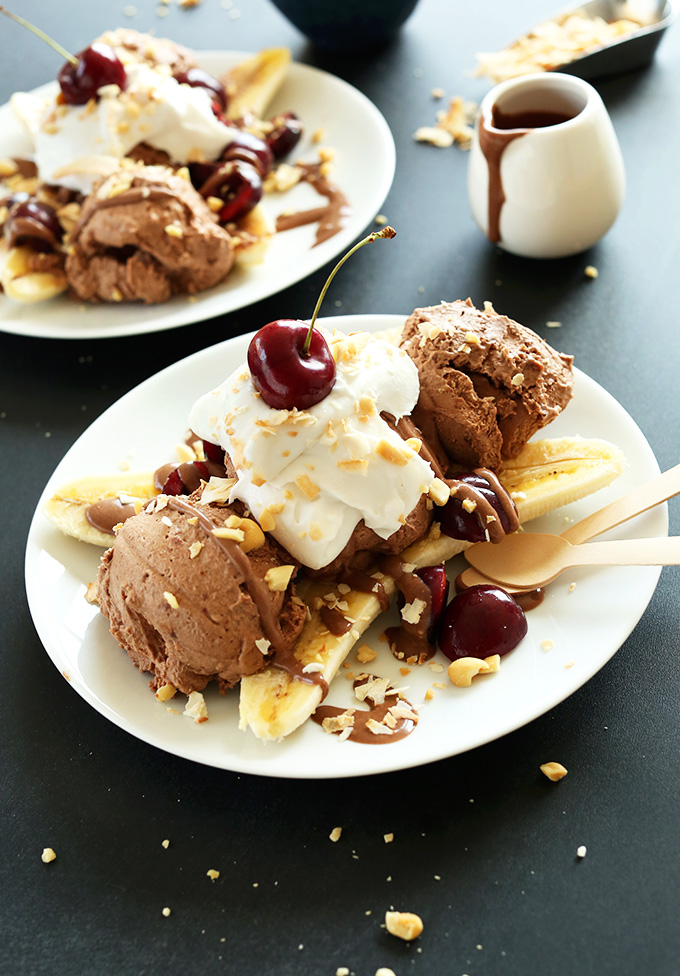 Banana topped with chocolate ice cream, peanuts, cherries, and coconut whipped cream for a Vegan Banana Split