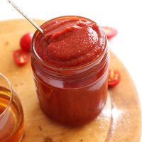 Spoon in a jar of homemade Whiskey BBQ Ketchup on a wood cutting board