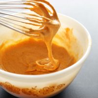 Vegan Mexican Queso falling off a whisk into a bowl