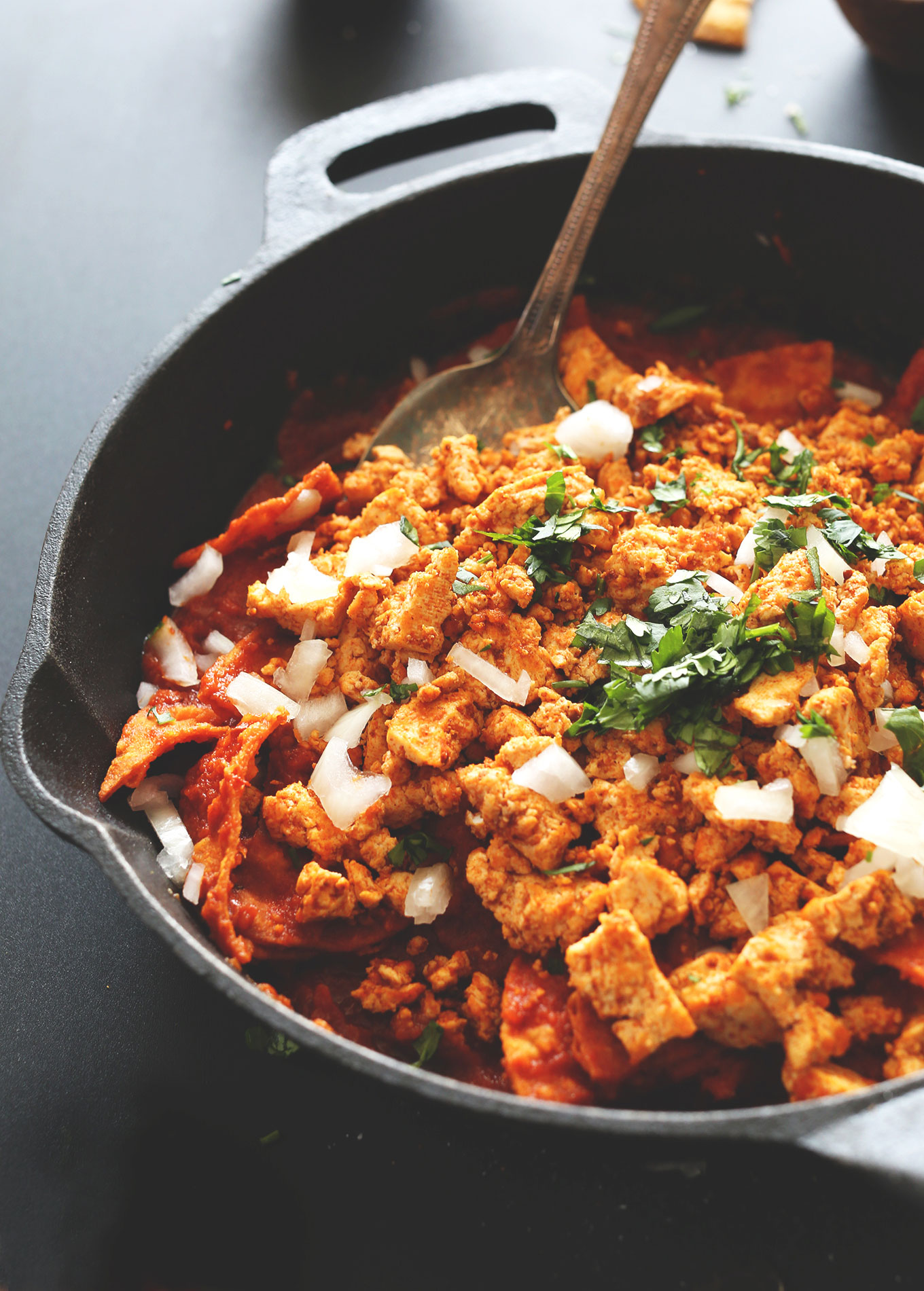 Pan of Vegan Tofu Chilaquiles topped with fresh cilantro and onion