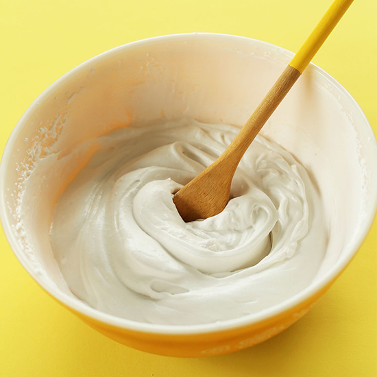 Wooden spoon in a bowl of homemade Coconut Whipped Cream