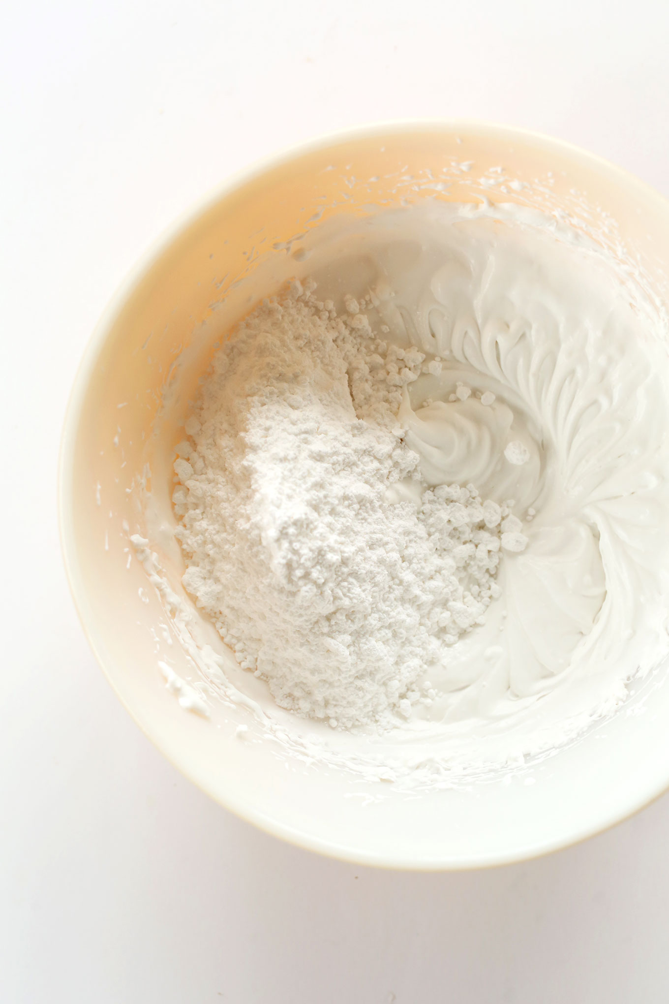 Powdered sugar in a bowl of whipped coconut cream