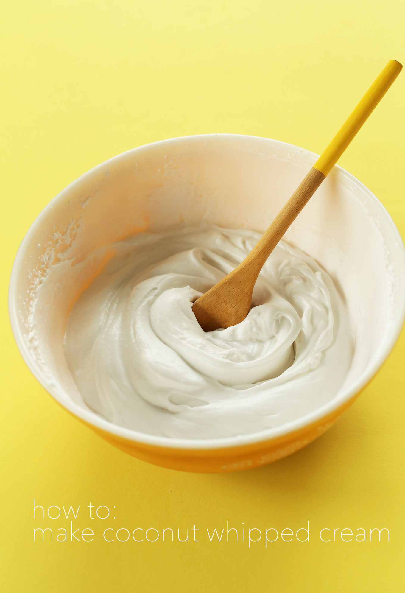 Wooden spoon in a bowl of homemade Coconut Whipped Cream made with our favorite brand of coconut cream
