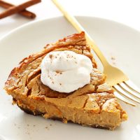 Plate with a slice of Vegan Pumpkin Swirl Cheesecake topped with coconut whipped cream