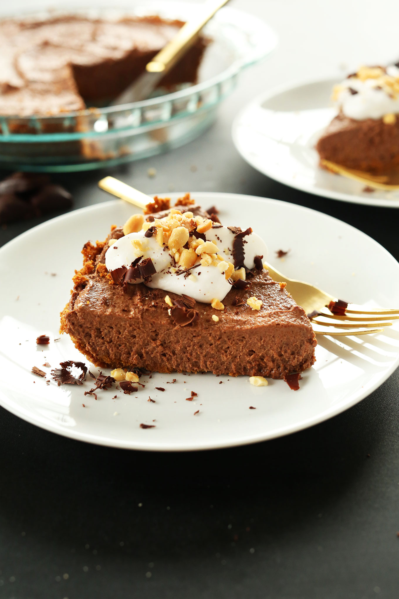 Slice of Vegan Chocolate PB Mousse Pie topped with coconut whip, shaved chocolate, and peanuts