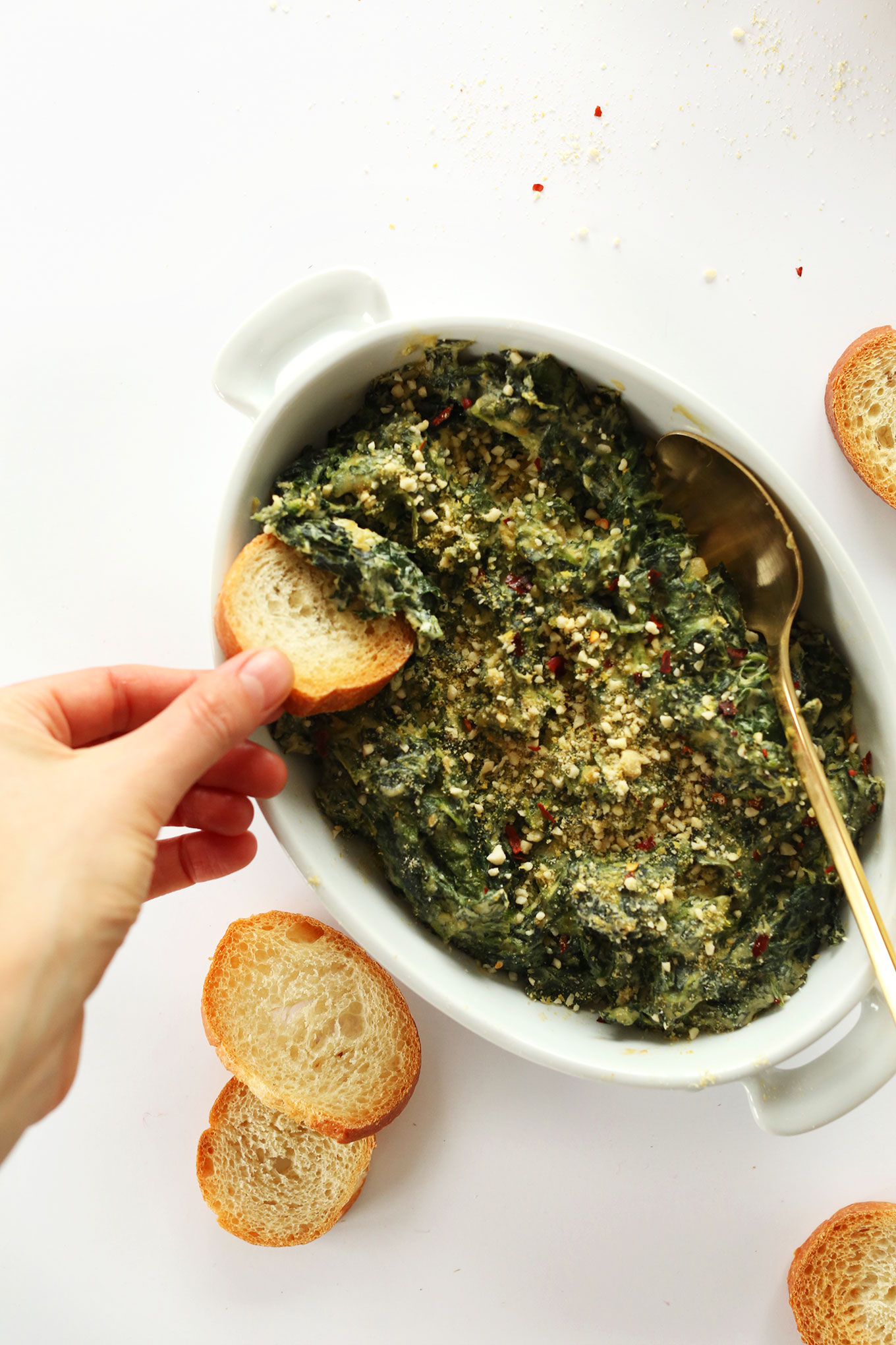 Dipping a slice of bread into our Creamy Vegan Kale and Spinach Dip