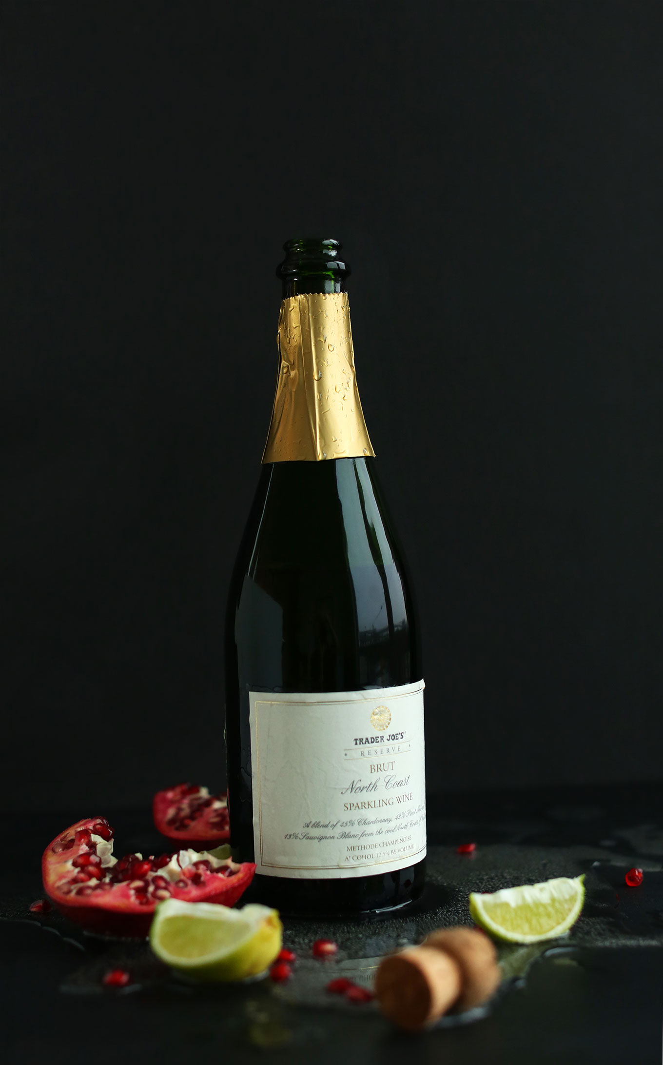 Bottle of champagne surrounded by fresh fruit of making a New Year's drink recipe