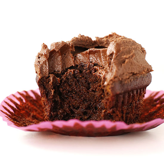 Partially eaten Vegan Gluten-Free Chocolate Cupcake on a pink wrapper