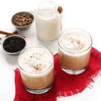 Dairy-free milk, spices, and two glasses of our homemade Vegan Chai Latte recipe