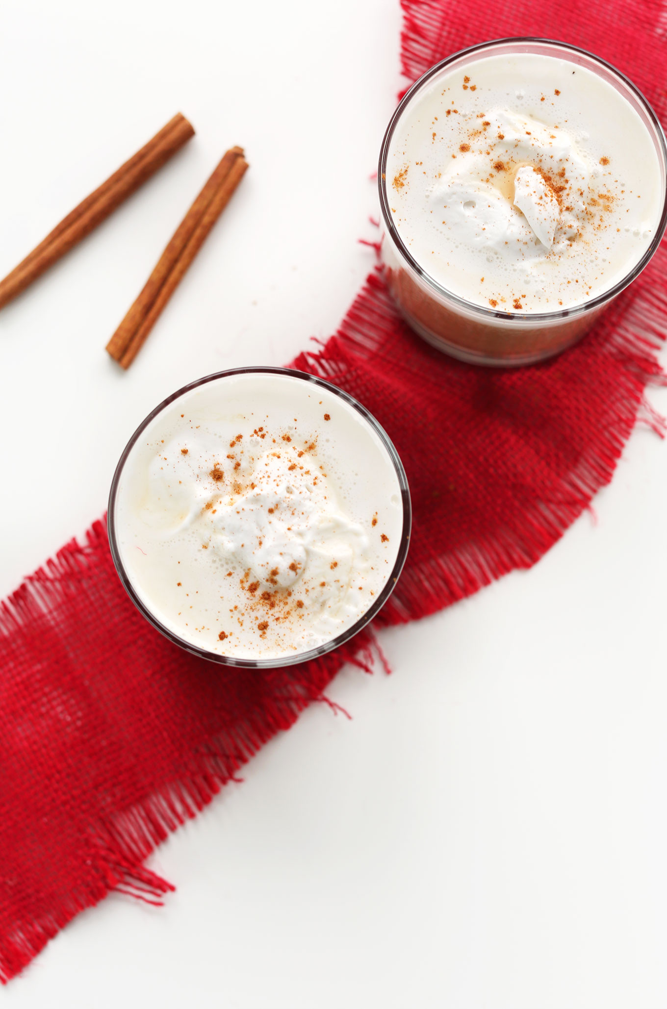 Two glasses of our Vegan Chai Latte recipe with coconut whip and cinnamon