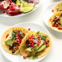 Plate with two Vegan Breakfast Tacos made with black beans, avocado, and pomegranate seeds