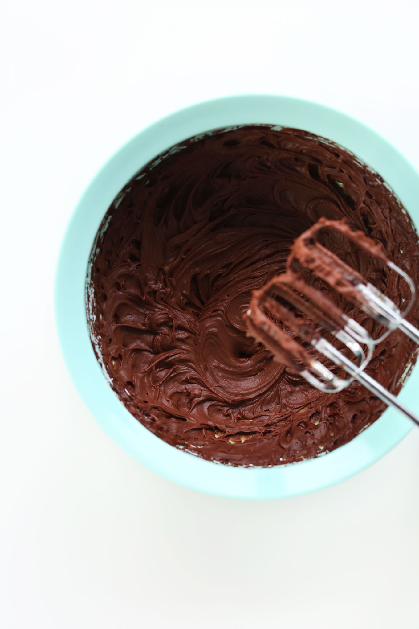 Electric mixer blades resting over a bowl of Vegan Chocolate Ganache Frosting