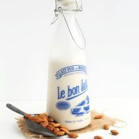 Scoop of almonds beside a jug of homemade almond milk