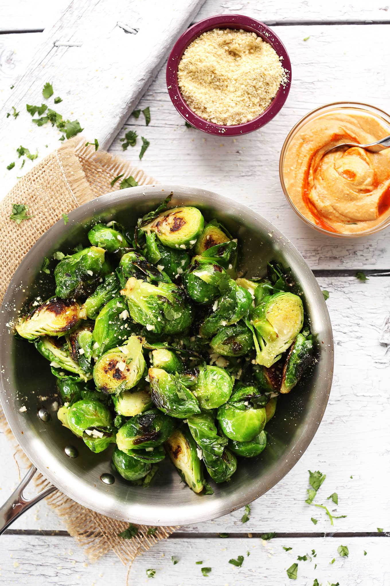 Pan filled with Crispy Brussels Sprouts alongside a bowl of Sriracha Aioli