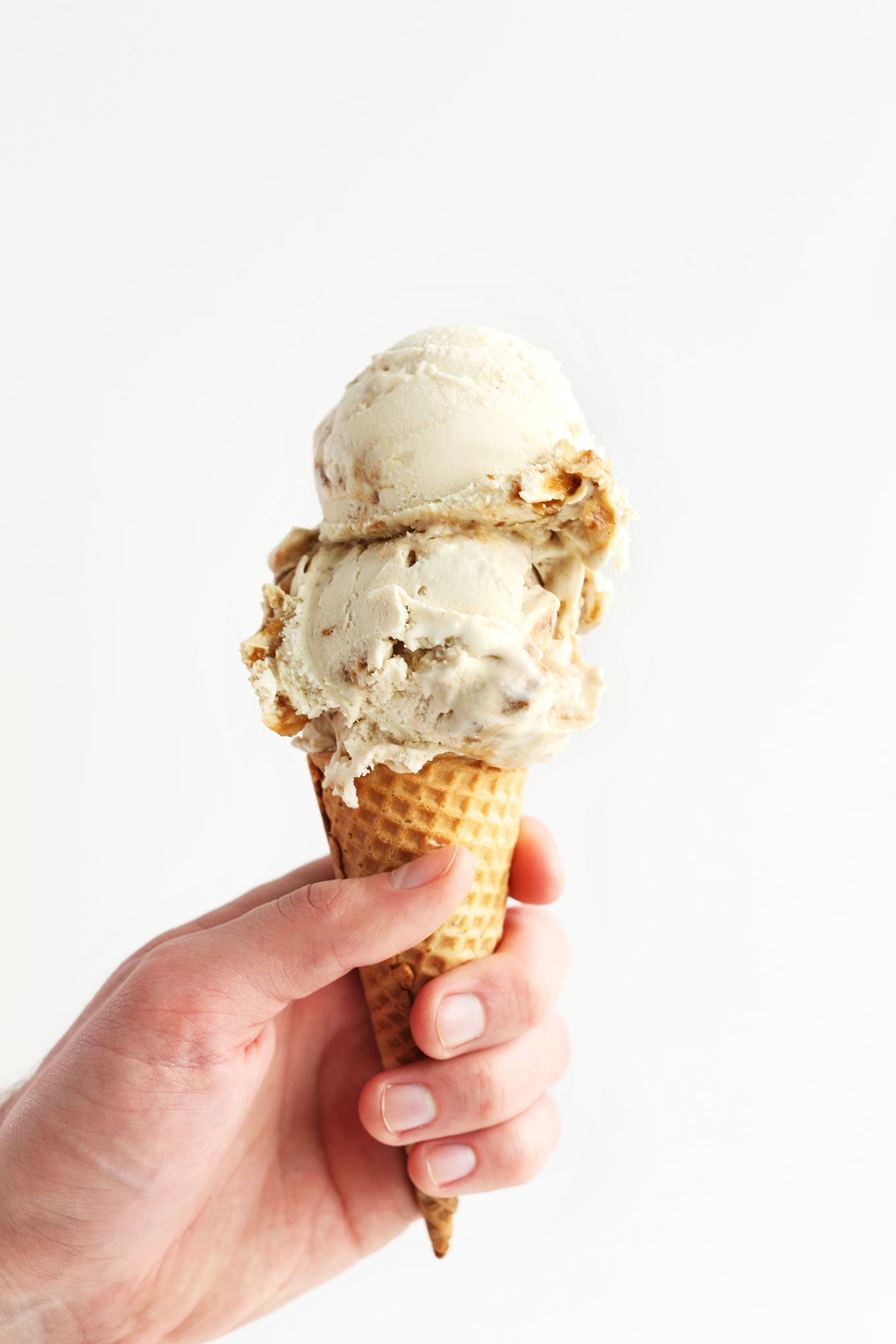Holding up an ice cream cone topped with scoops of homemade Vegan Coconut Caramel Sea Salt Ice Cream