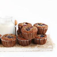 Batch of homemade Gluten-Free Coconut Berry Muffins on a wood board with a jar of dairy-free milk